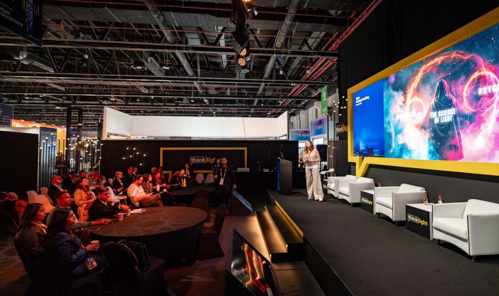 A speaker presenting on stage at a lighting conference.