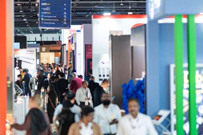 A crowded exhibition hall with booths and visitors.