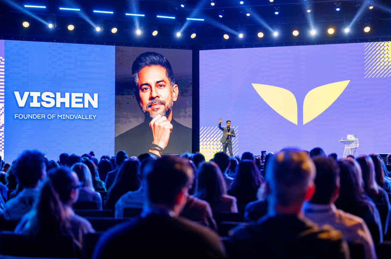 Wide shot of a conference hall at Future Human 2025 in Dubai, showing the stage with large screens, the event logo, and keynote speaker Vishen Lakhiani in front of a seated audience.