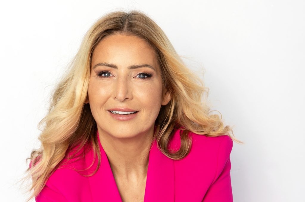 Close-up portrait of Dr. Heike Lieb-Wilson wearing a bright pink blazer in front of a white background, smiling softly at the camera.