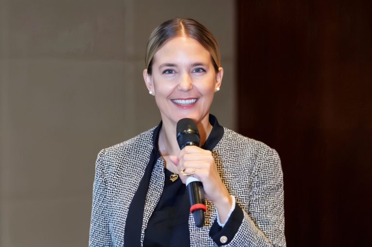 Close-up of Anna Thiel holding a microphone and smiling while speaking on stage about leadership and personal clarity.
