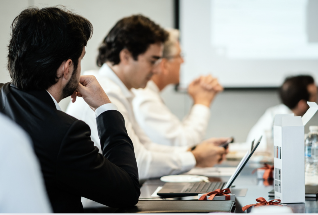 Corporate professionals in a formal meeting environment, focused on teamwork and collaboration.