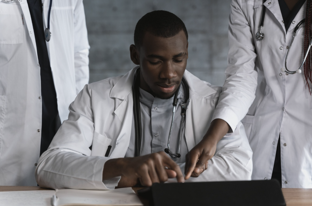 Medical professionals collaborating around a laptop in a modern healthcare setting.