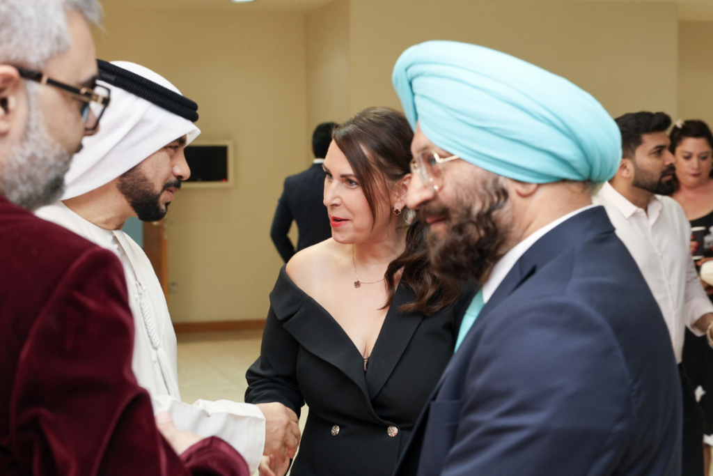 Businesswoman in a black suit shaking hands with Emirati and international business leaders during a professional networking event in Dubai.