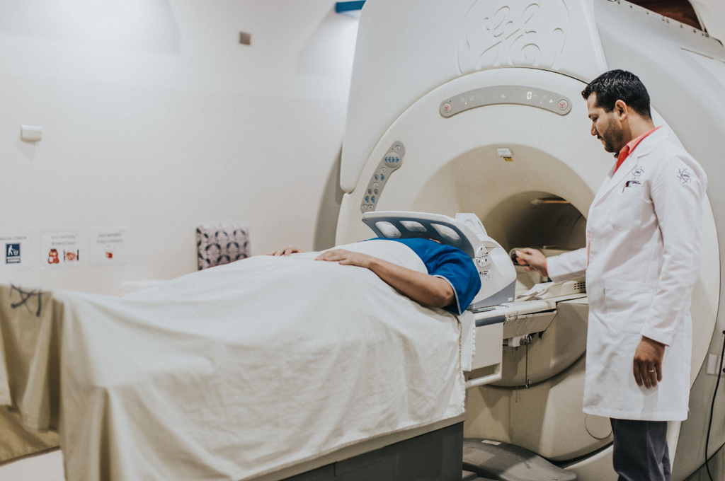 Doctor operating an MRI scanner as a patient undergoes advanced medical imaging